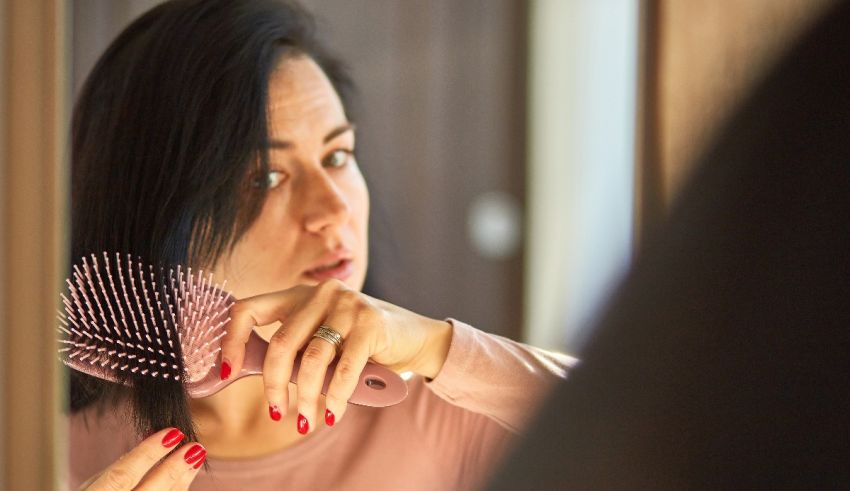 A woman is brushing her hair in front of a mirror.
