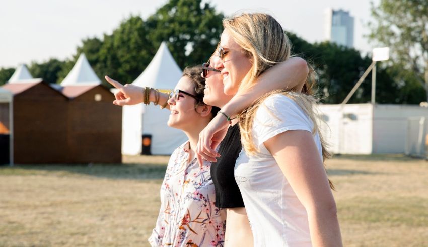Three women standing in a field with a tent in the background.