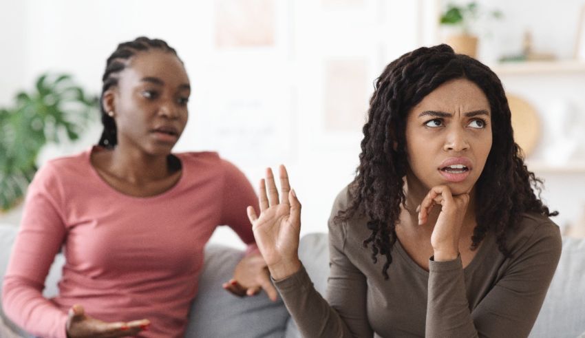 Two women sitting on a couch talking to each other.