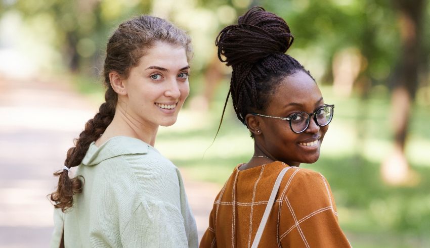 Two young women standing next to each other in a park.