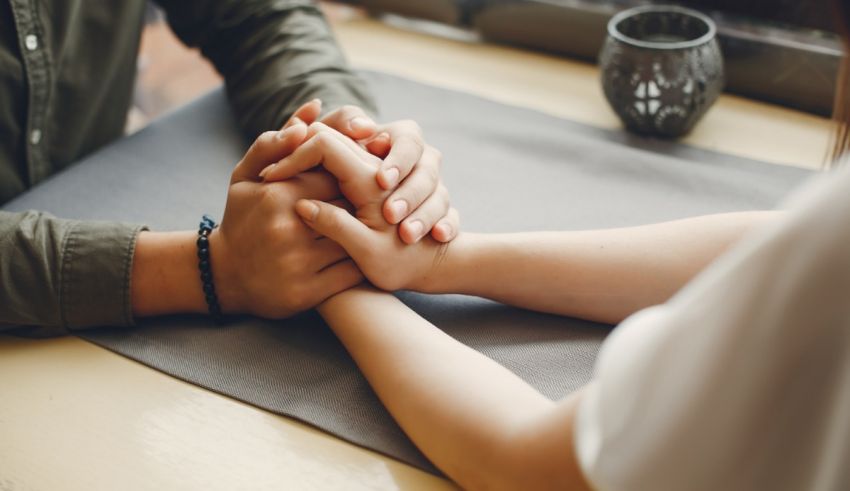 A man and woman holding hands on a table.