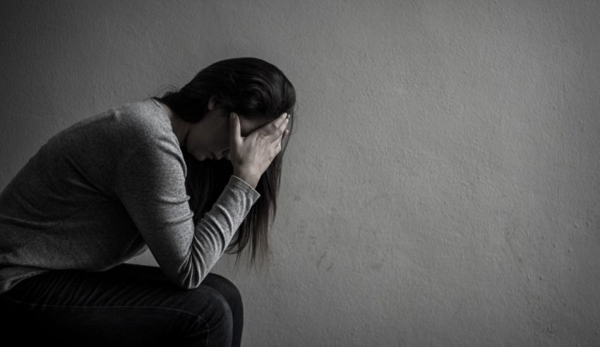A woman is sitting on the floor with her hands on her head.