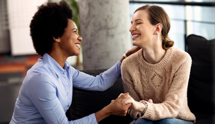 Two women sitting on a couch talking to each other.