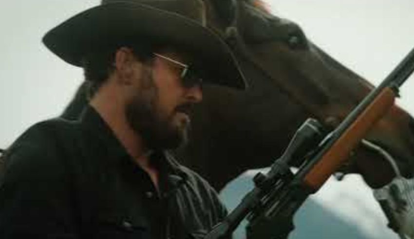 A man holding a rifle next to a horse.