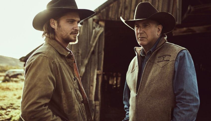 Two men in cowboy hats standing in front of a barn.