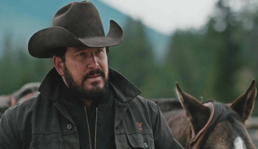 A man in a cowboy hat standing next to a horse.