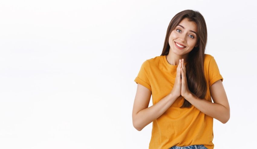 A young woman is posing with her hands folded.