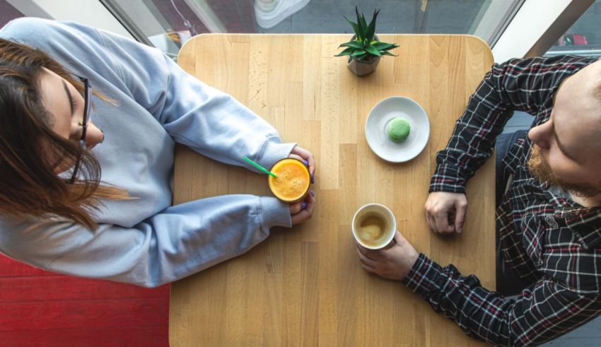 Two people sitting at a table and drinking orange juice.