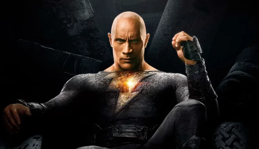 A bald man is sitting in a chair with his hands in his pockets.