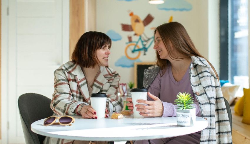 Two women in pajamas sitting at a table drinking coffee.