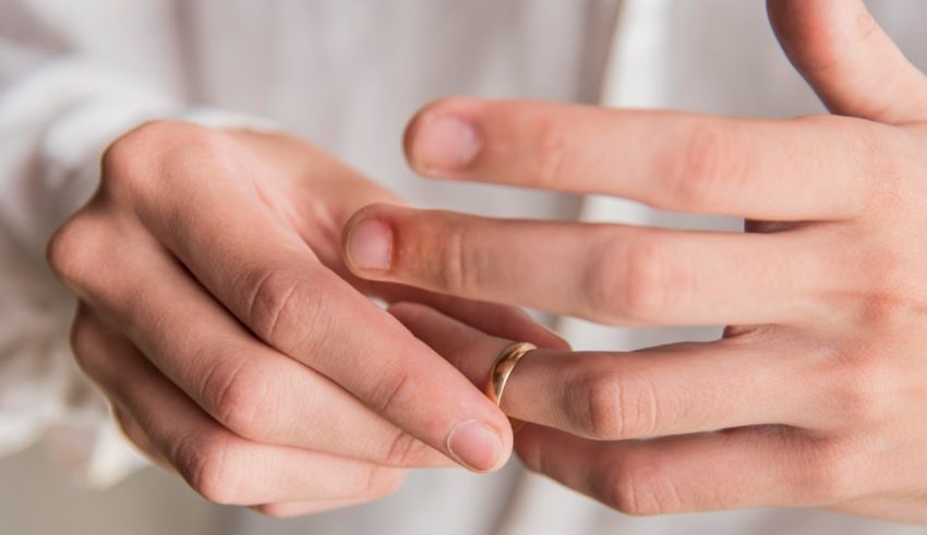 A man is putting a wedding ring on his hand.