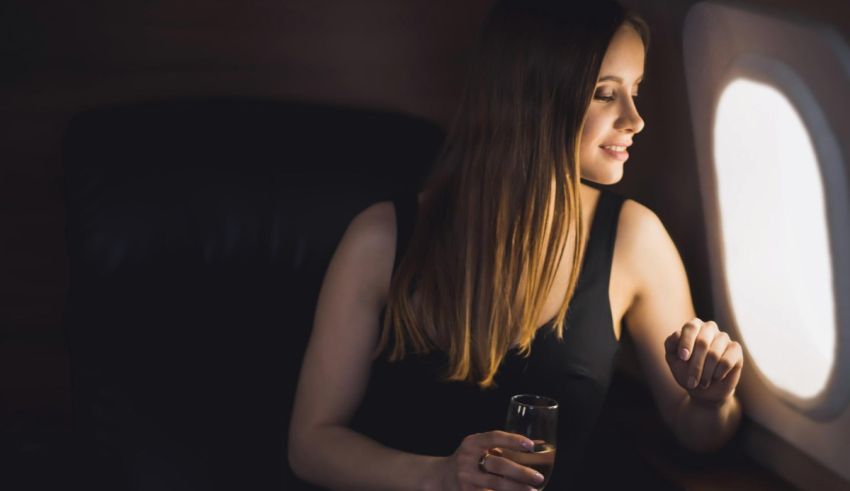 A woman holding a glass of wine while looking out the window of an airplane.