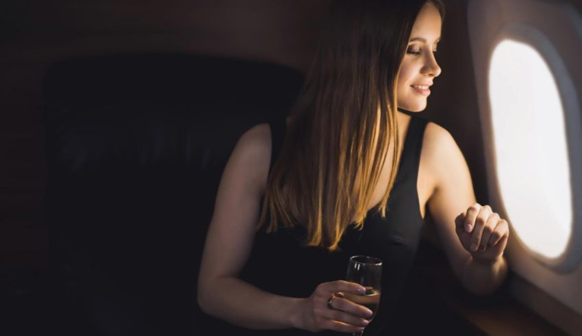 A woman is sitting in an airplane with a glass of wine.
