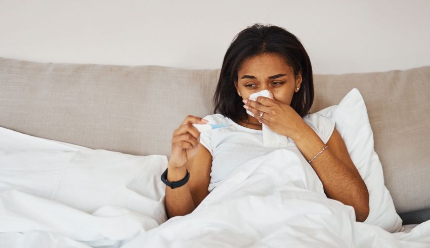 A woman sneezing and blowing her nose in bed.