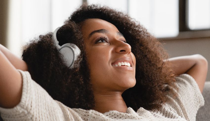 A woman with curly hair listening to music on headphones.