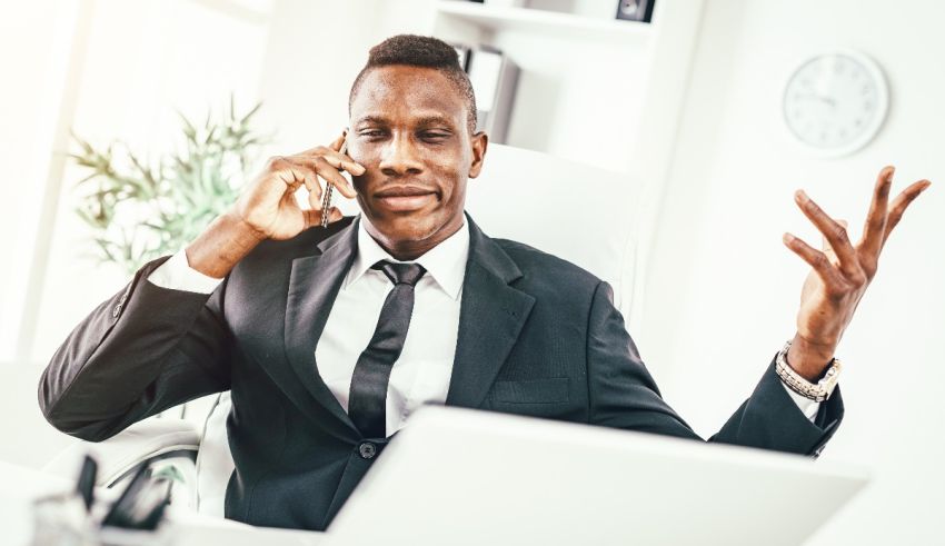 A businessman talking on the phone while sitting at his desk.