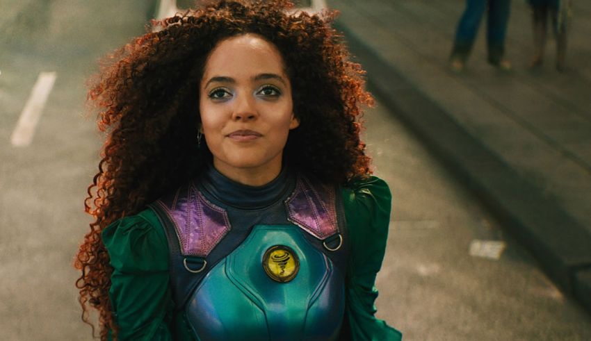 A woman in a green and purple costume is standing on the street.