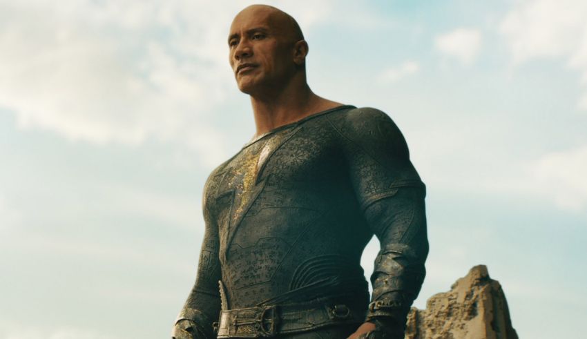 A bald man in a suit standing on a rock.