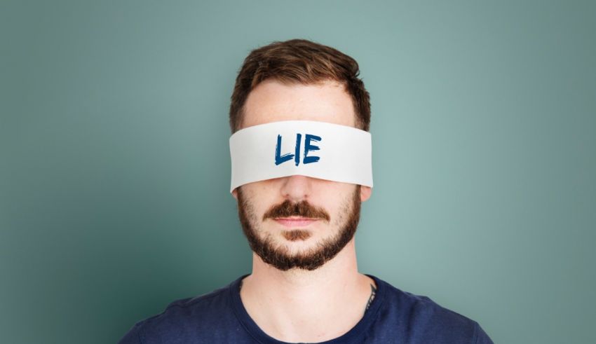 A man with a blindfold covering his eyes with the word lie.
