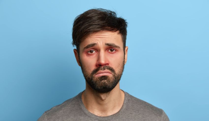 A man with red eyes and a beard on a blue background.