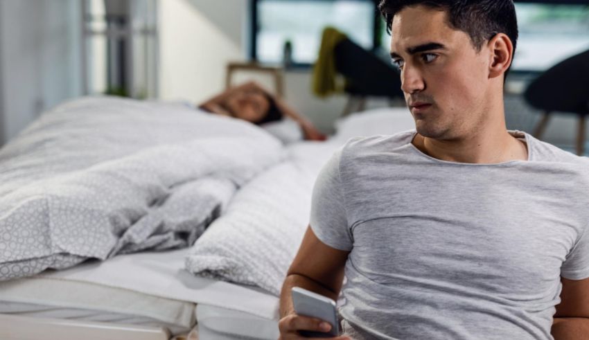 A man looking at his cell phone in bed.