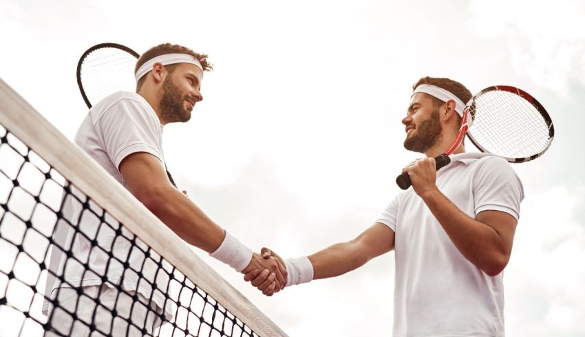 Two tennis players shaking hands in front of a net.
