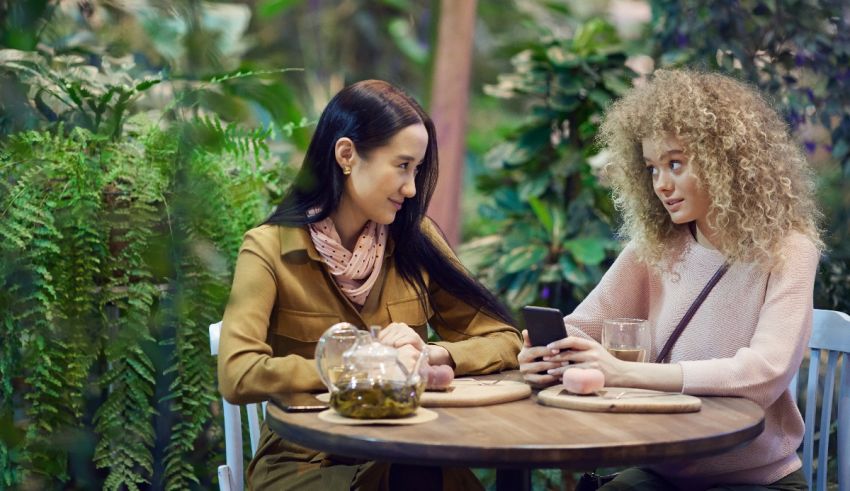 Two women sitting at a table in a garden.