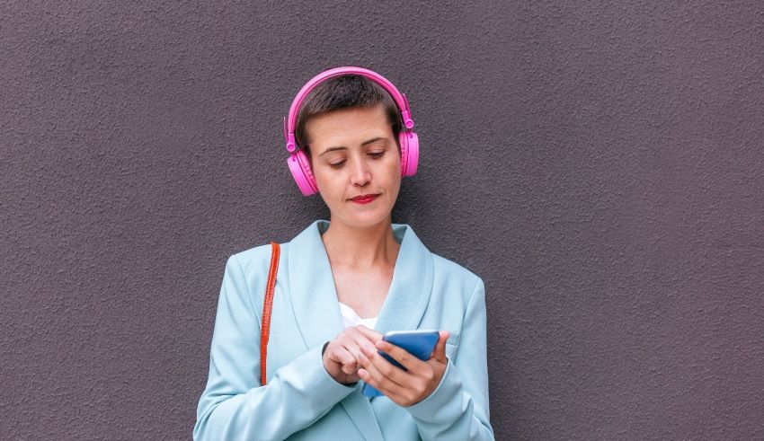 A woman wearing pink headphones and holding a cell phone.