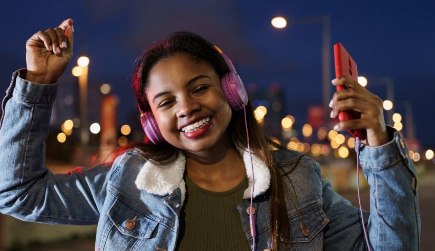 A young woman wearing headphones and holding a phone at night.
