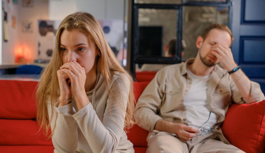 A man and woman sitting on a red couch.