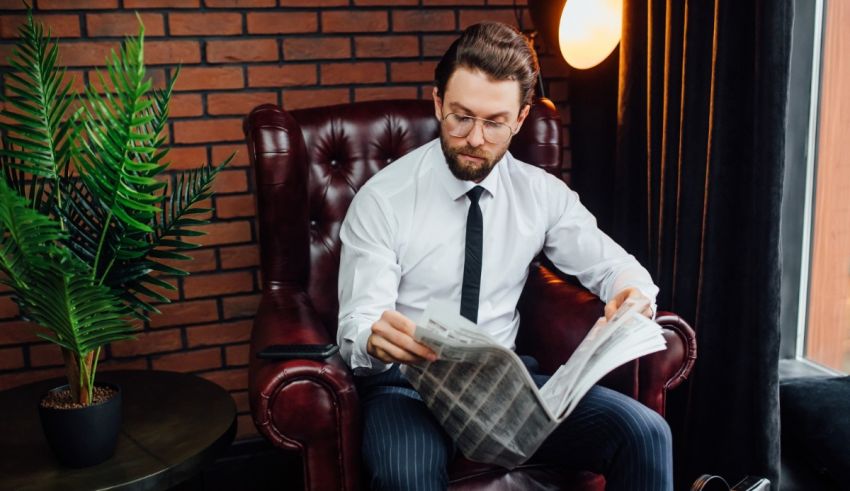 A man sitting in a chair reading a newspaper.