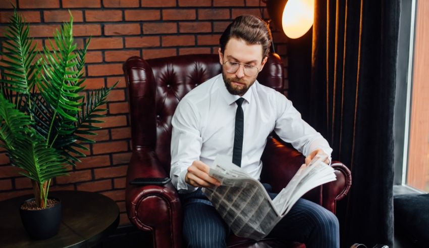 A man sitting in a chair reading a newspaper.
