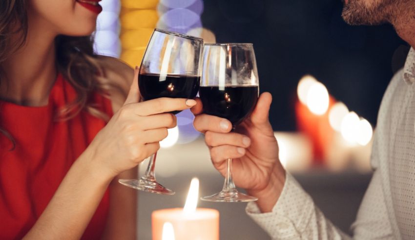 A man and woman toasting wine glasses in front of candles.