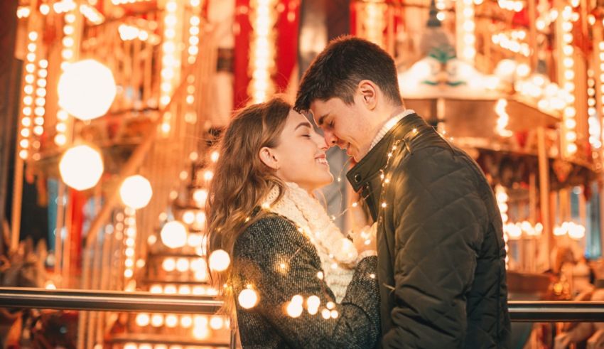 A couple kissing in front of a carousel.