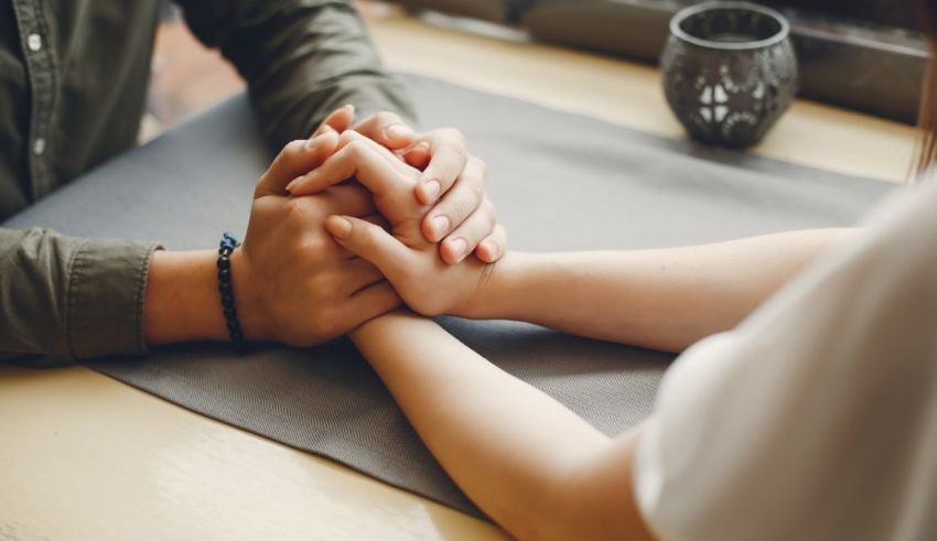 A man and woman holding hands on a table.