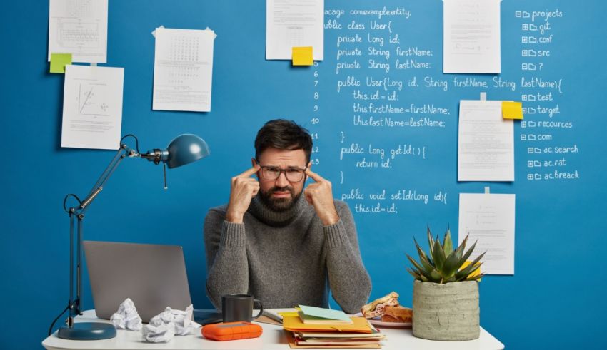 A man sitting at a desk with sticky notes on the wall.