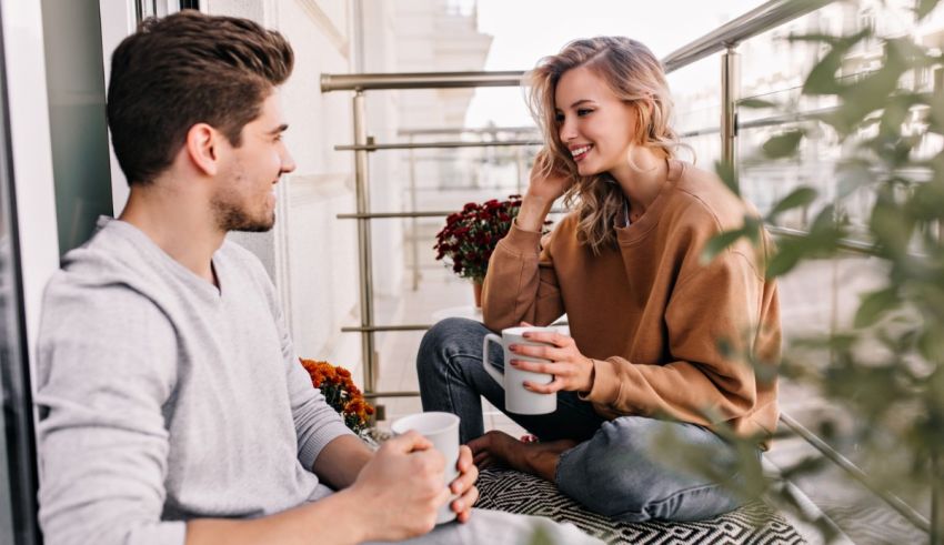 A man and woman sitting on a balcony talking to each other.