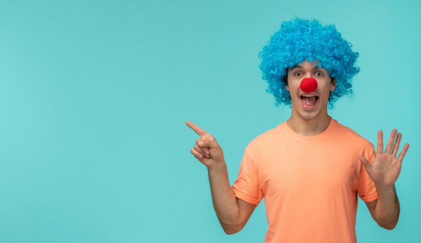 A young man wearing a blue clown wig is pointing his finger.