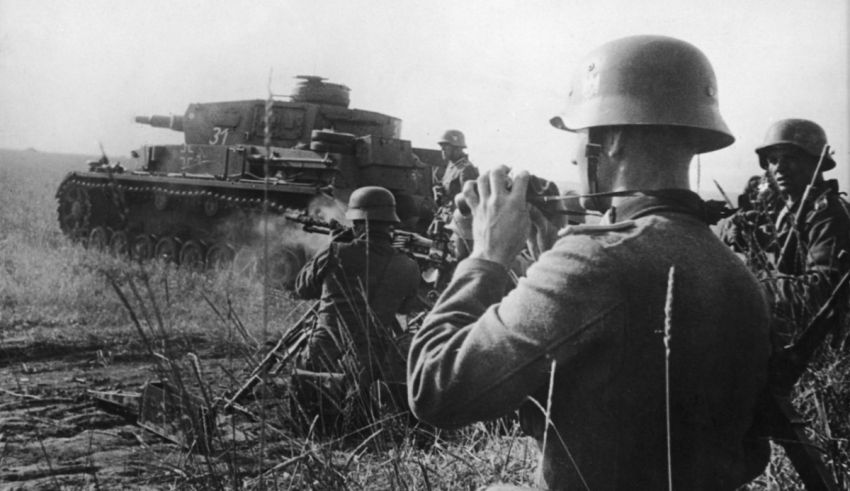 A group of soldiers standing in front of a tank.