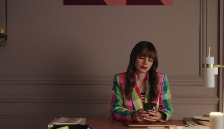 A woman sitting at a desk with a cell phone.