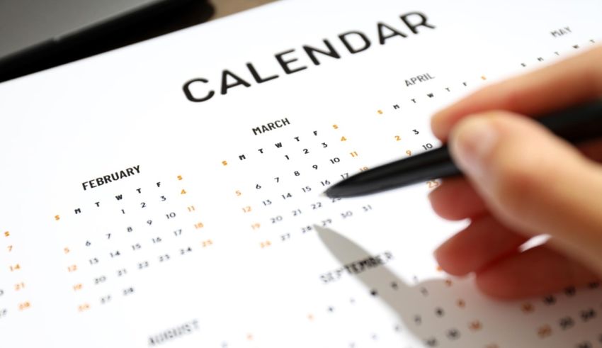 A person writing on a calendar with a pen.