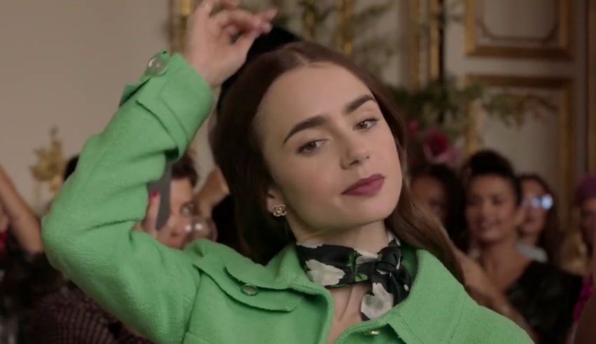 A woman in a green coat is dancing in front of a crowd.