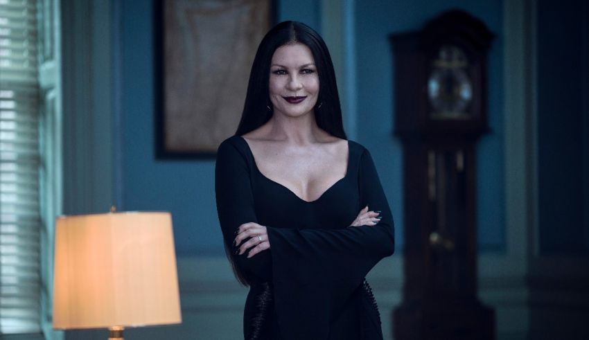 A woman in a black dress standing in front of a lamp.