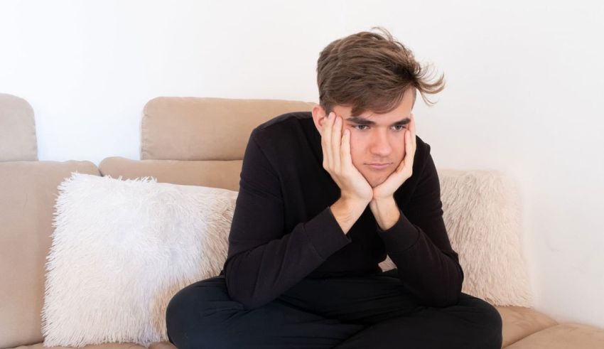 A man sitting on a couch with his hand on his face.