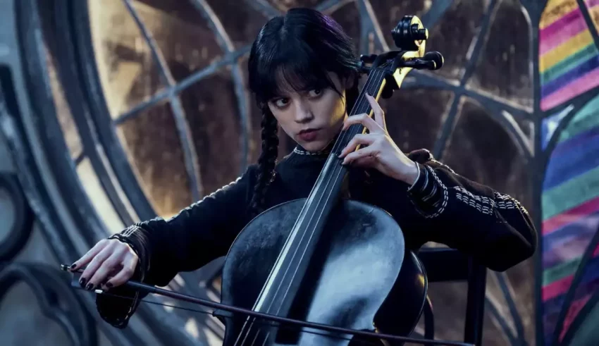 A woman playing a cello in front of a stained glass window.
