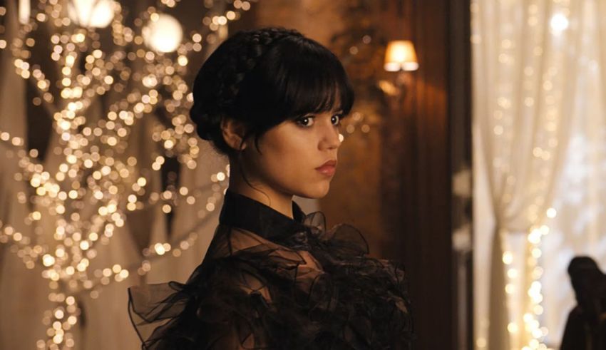 A woman in a black dress standing in front of lights.