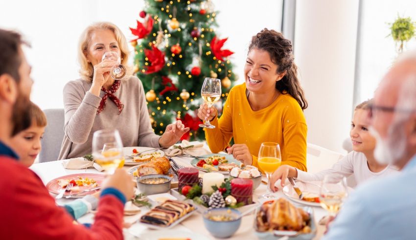 A family having a christmas dinner in front of a christmas tree.