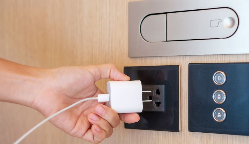 A person is using a power outlet in a hotel room.