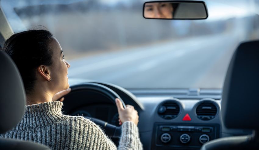 A woman is driving a car while looking at her reflection in the mirror.