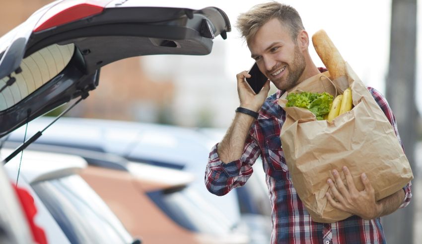 A man talking on the phone while holding a shopping bag.